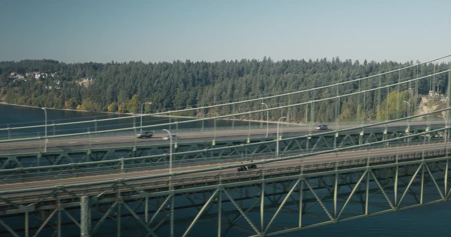 Two motorcycles traveling across a suspension bridge