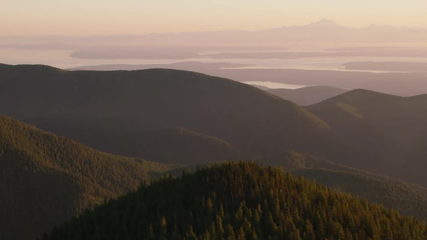 Aerial panorama of mountains with green forests seen at sunrise