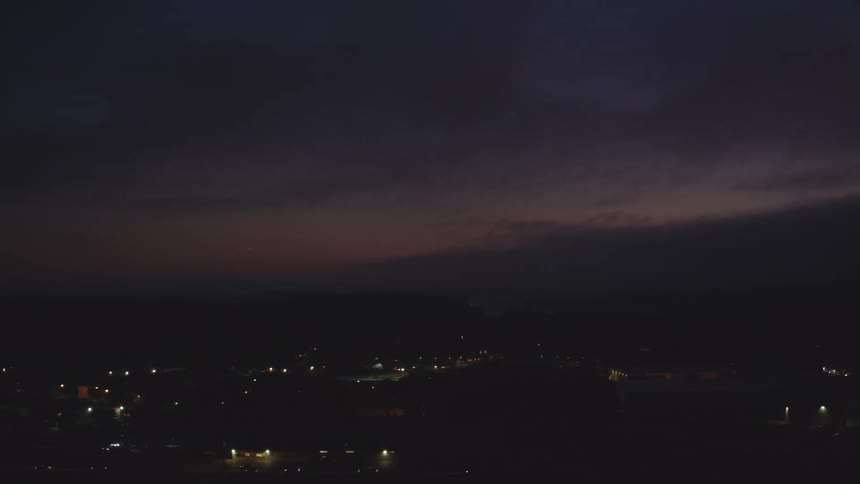 Aerial and moving view of an urban city seen at night and a purple sky
