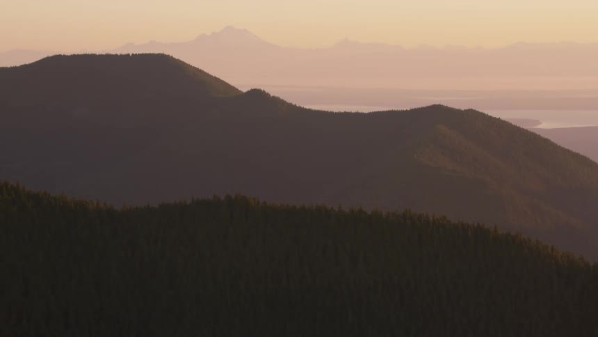 Forested mountain ranges against the reddish dawn sky