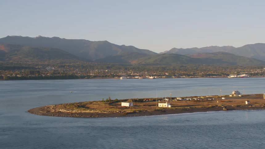 Aerial view of rural houses on an island surrounded by sea with mountains on the horizon