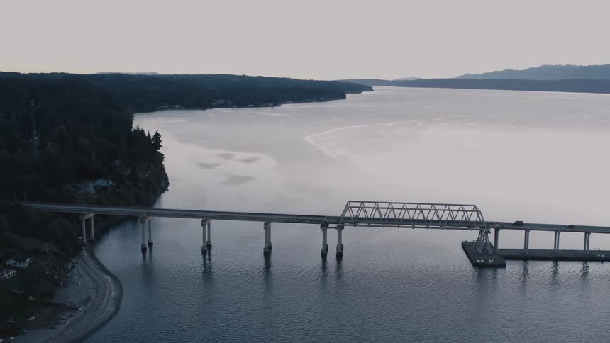 A vehicle travels over the bridge on the river