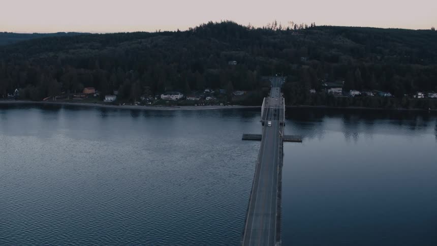 Aerial view of a bridge crossing the sea and giving access to a city on a hill surrounded by vegetation