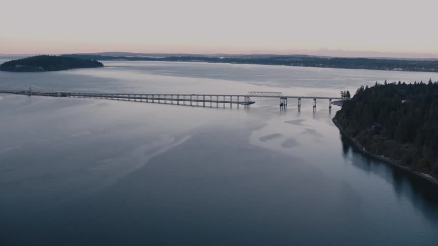 Aerial of a car driving across a bridge that connects forested islands