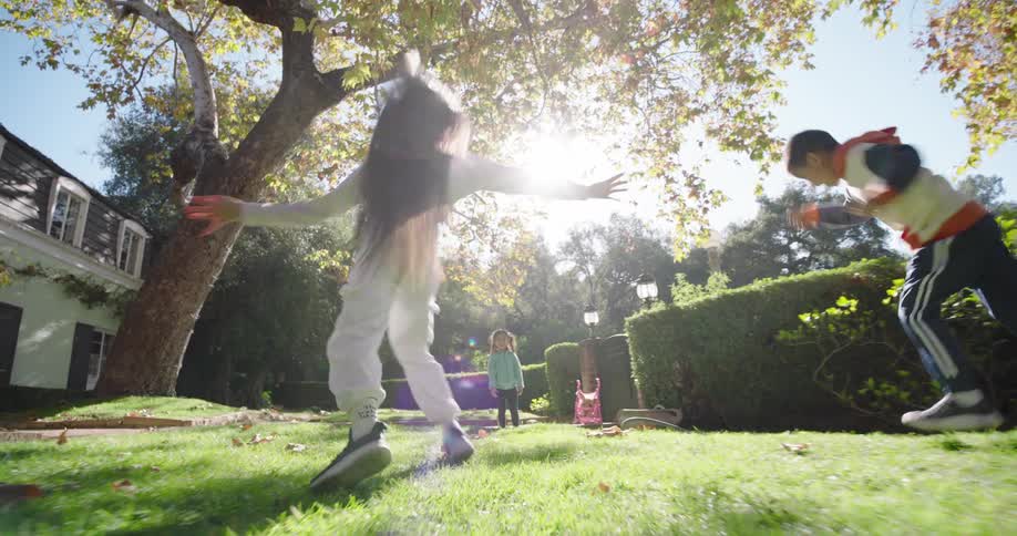 Two children perform energetic flips and handstands on a sunlit lawn surrounded by trees and a house capturing a moment of playful movement