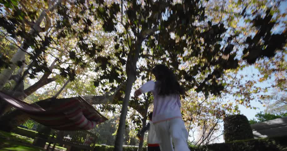 A girl chases a boy in the yard