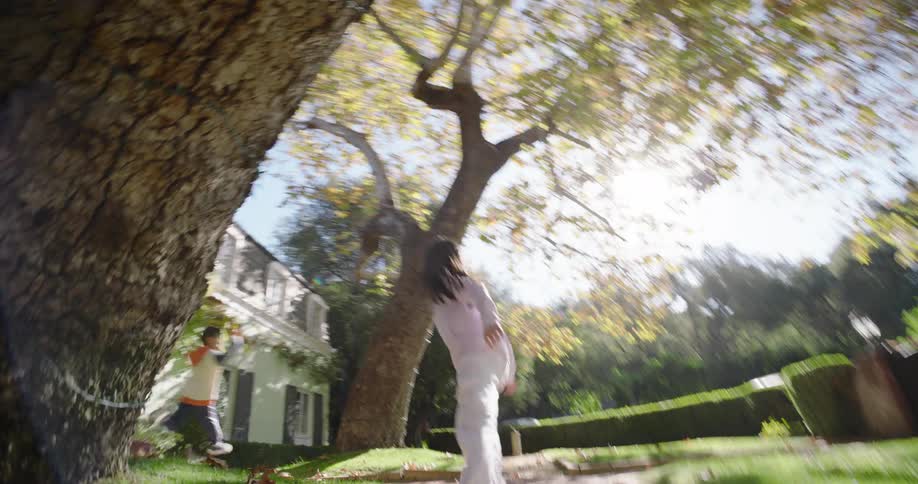 Siblings play tag in the large yard of their home on an autumn day