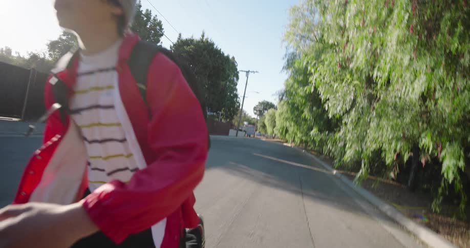 A boy rolls down the block on his skateboard