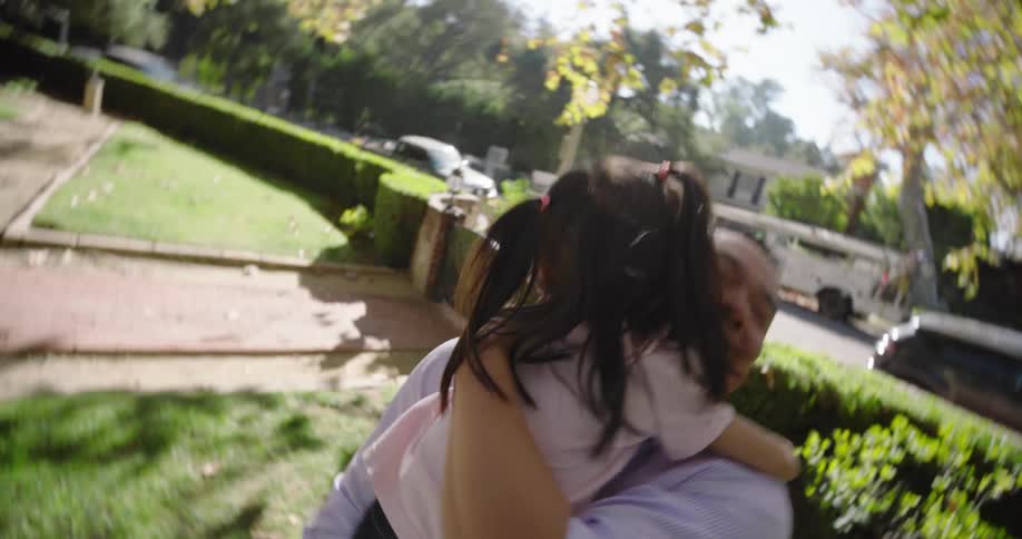 Father and daughter smile while playing together on the front lawn of their house on a sunny day