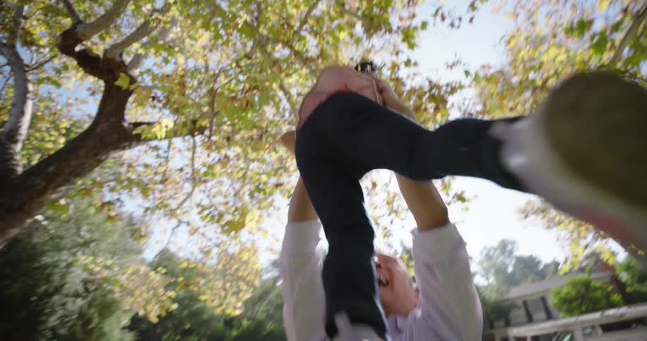 A girl runs into her fathers arms in the yard