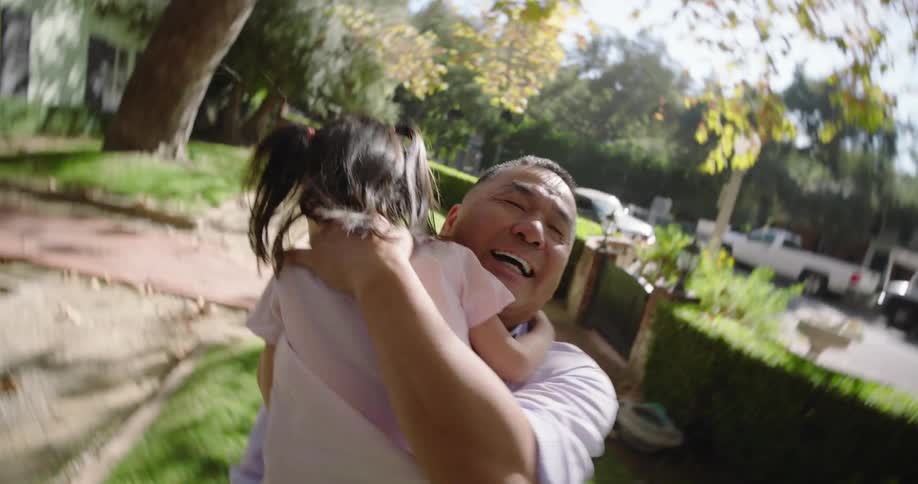 A father hugs and lifts up his daughter