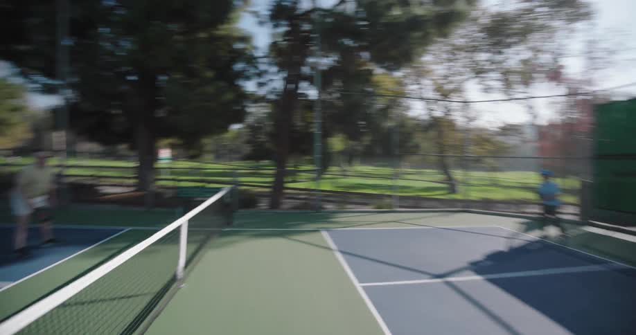 Four people are playing pickleball on a court on a sunny autumn day