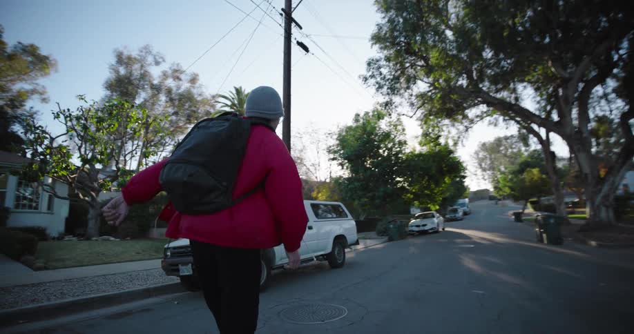 A teenage boy rides a skateboard in a residential neighborhood