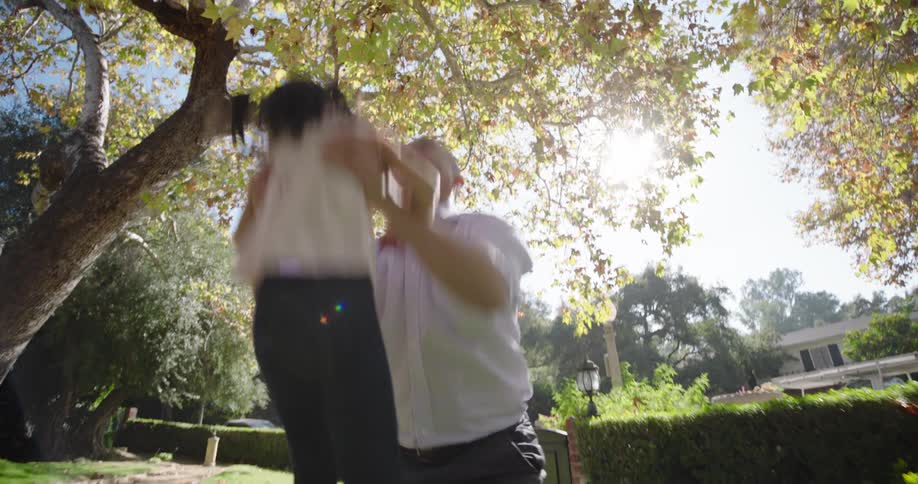 A father lifts his daughter up into the air