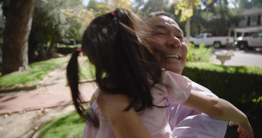 A little girl being held by a man who is holding her upside down and she is happy and we win they are hugging each other