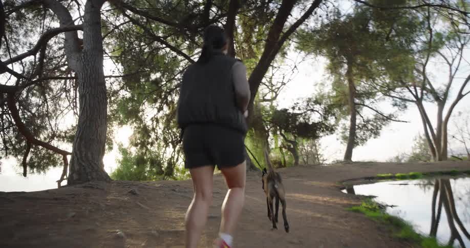 A woman runs by the water with her dog