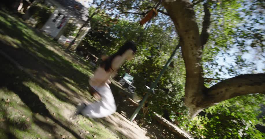 Young girl swings on a tree swing in her backyard