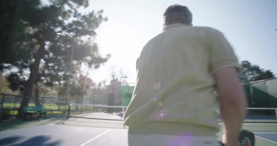 A person is playing tennis on an outdoor court serving a ball with a racket