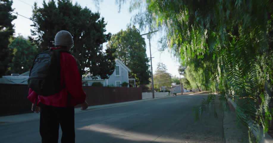 A teenager is skateboarding down the road