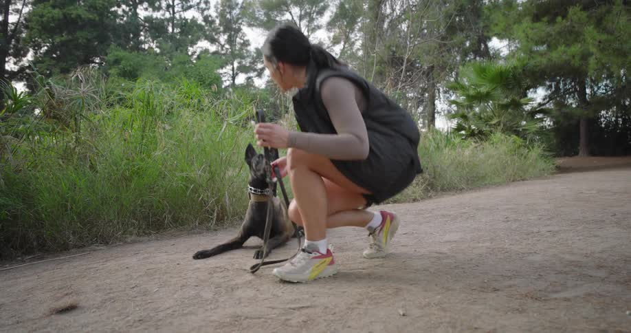 Woman ties her sneaker before starting to jog along a path with her dog