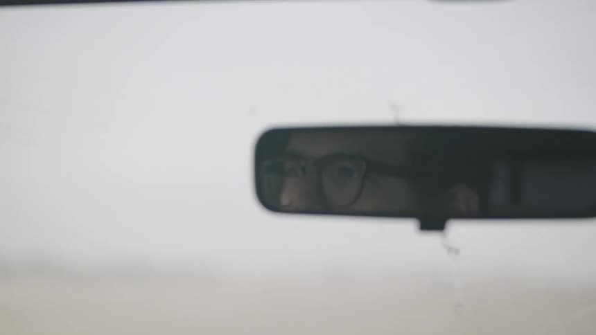 Man adjusts his rear view mirror as he drives