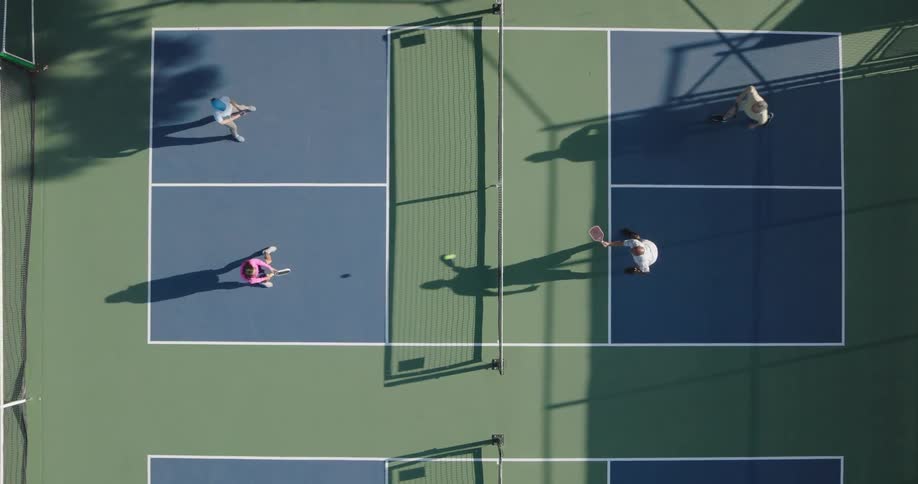 People are playing a game of pickleball on a sunny day