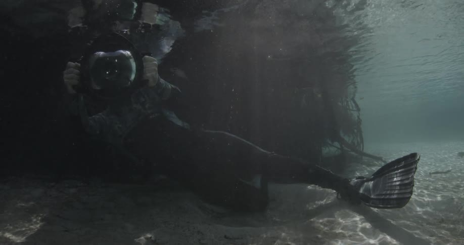 A scuba diver underwater taking photos with a large camera
