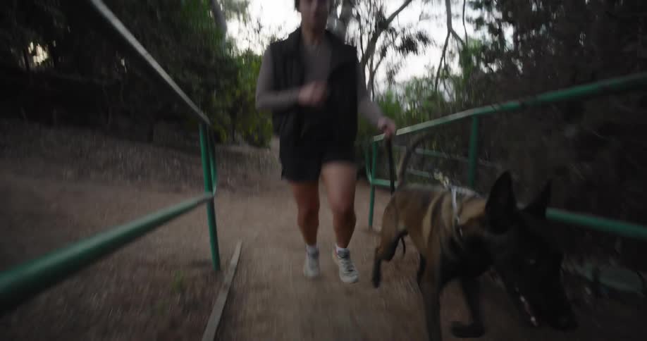 A woman is running with her dog on the park trail