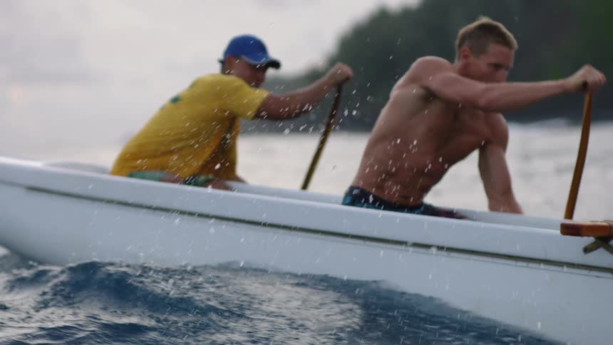 Men paddle near the shore in an outrigger