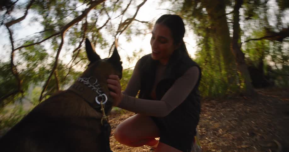 Woman playfully petting her dog on a hiking trail in the woods