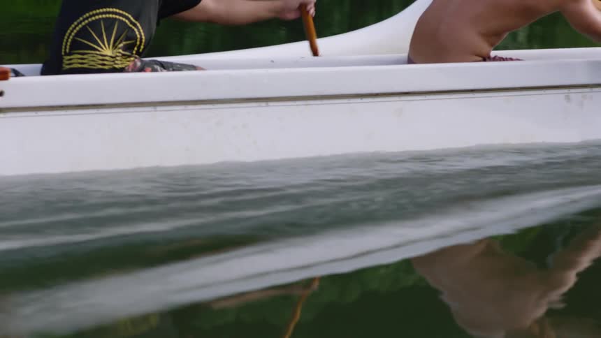 Three males in a canoe paddle slowly through the lake