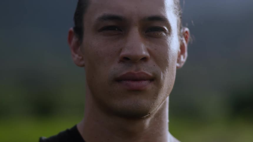 Closeup of the face of a person standing outdoors with a mountainous landscape in the background