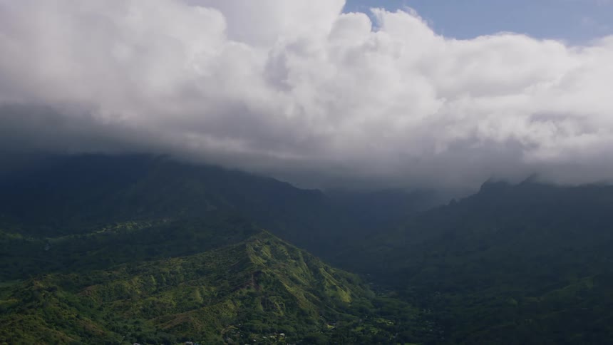 Heavy cloud bank flows over a foggy valley near mountainside buildings