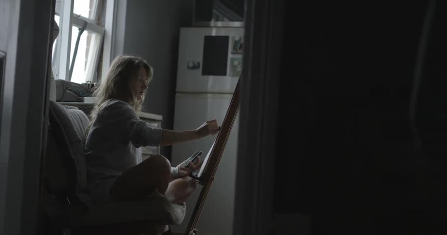 Woman painting on a canvas by a window