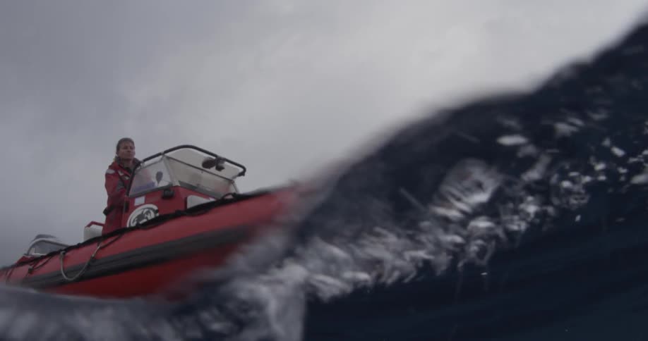 Red boat passing by the camera as seen exactly from surface level