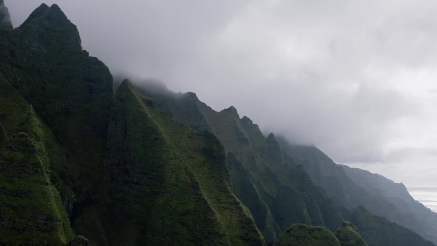Low lying clouds and fog partially cover steep vegetation covered mountain slopes