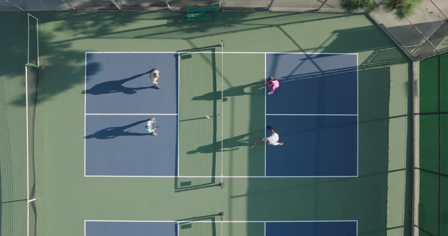 Aerial view of two pairs playing tennis on a court during daytime