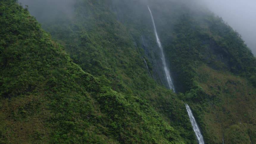 Aerial of a tall waterfall in a mountainous rainforest