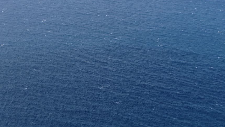 A view of the deep blue ocean surface with small waves and ripples visible