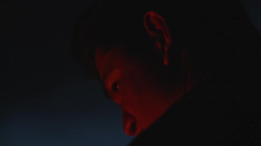 The close up of the face of a young man illuminated by a bonfire at night