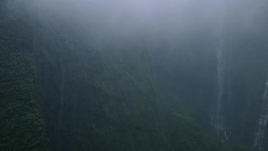 The waterfall and mountain are covered with mist
