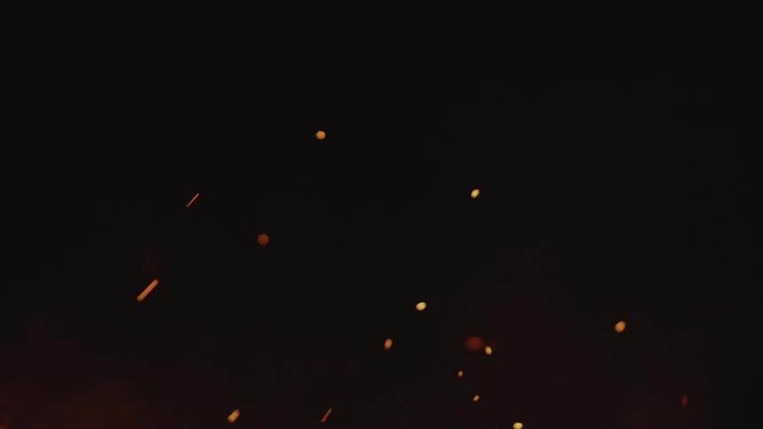 Embers rising from a bonfire at night
