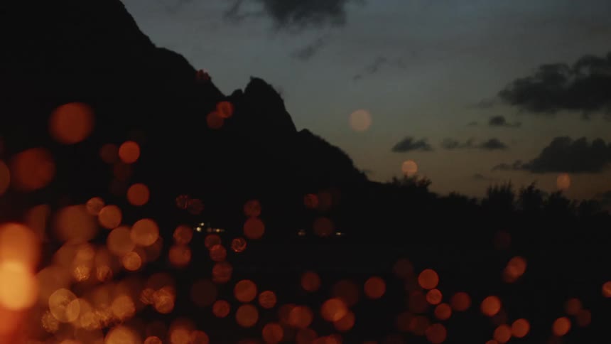 Some round and blurred orange decorate lights coming out from around a flame of fire in a dark region