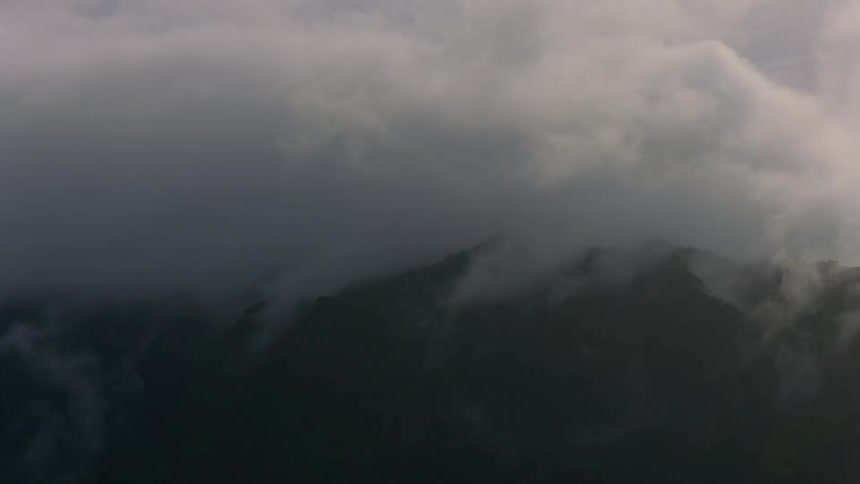 Low lying clouds partially obscure mountainous terrain during a cloudy day