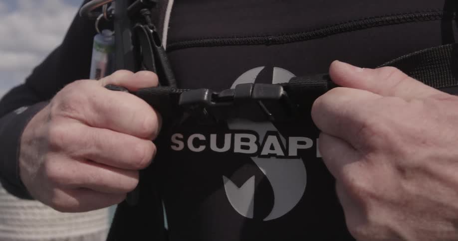 A man latches his scuba gear on