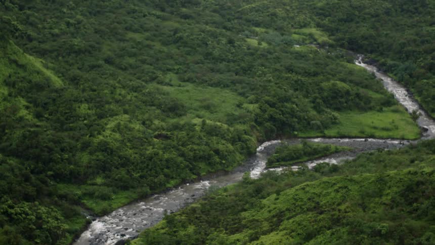 Aerial view of a winding river cutting through a green mountain