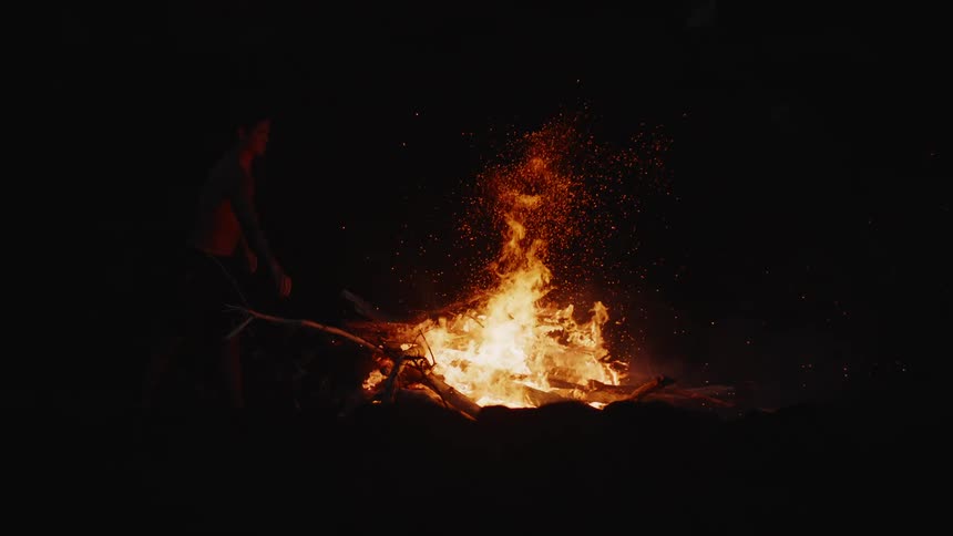 Person in the dark putting branches in a bonfire