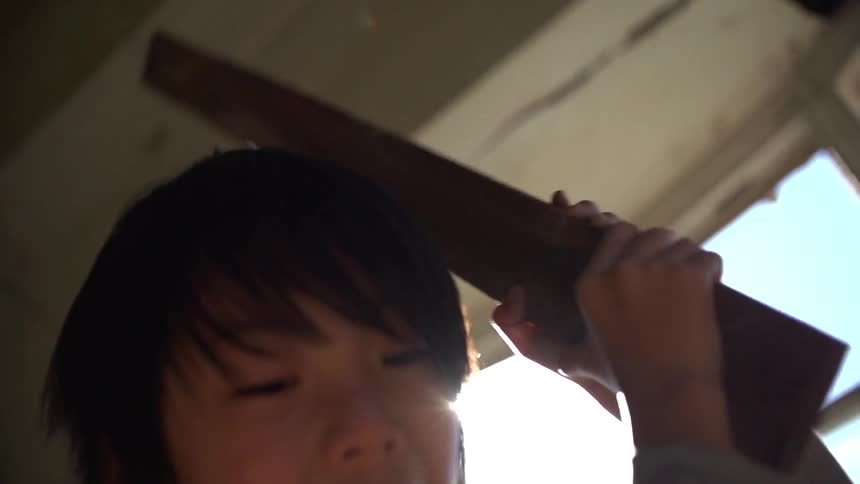 A boy swings a piece of wood