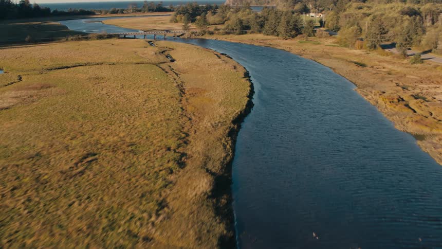 A river winding through marshland leading to a bridge in the distance