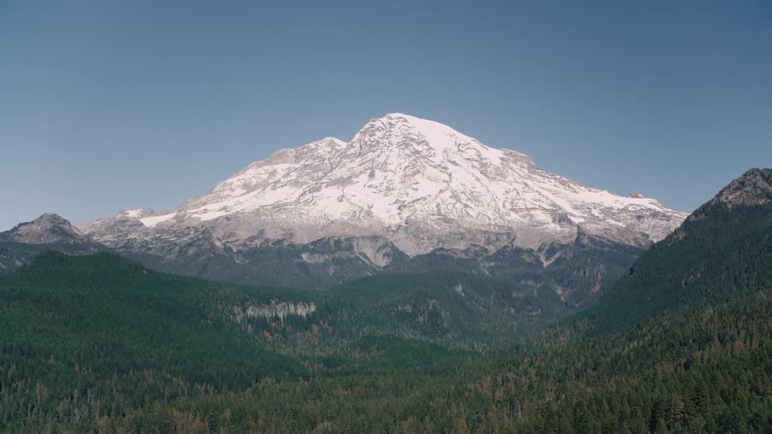 Aerial landscape of a dense forest in mountains and in the background another snowy mountain